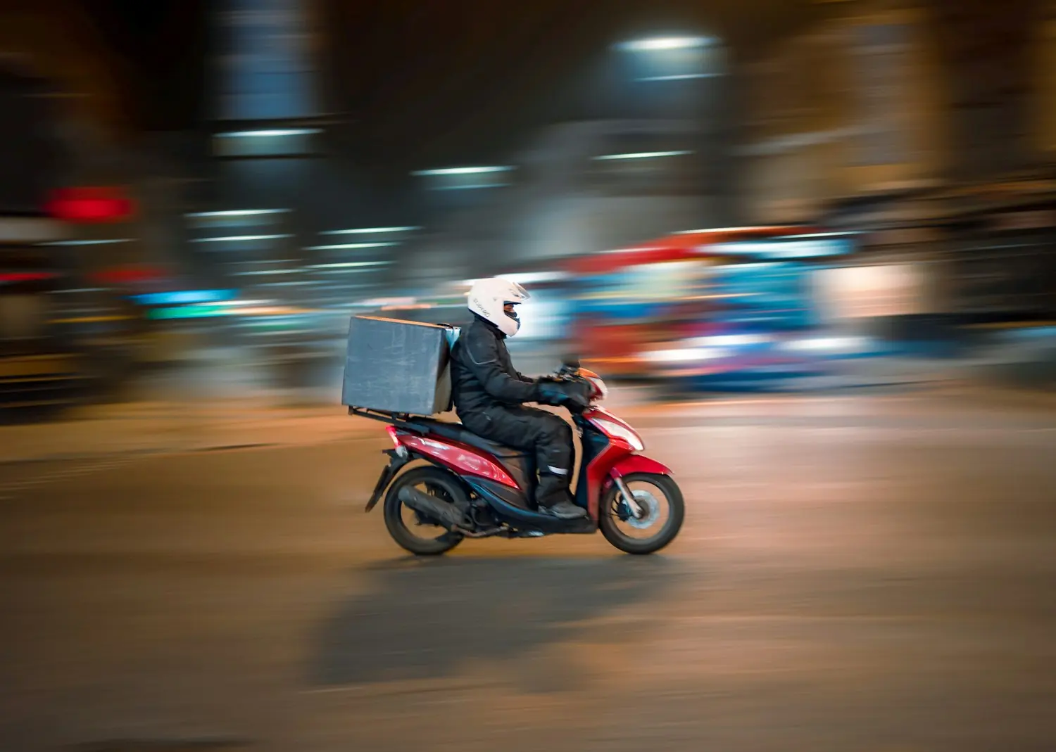 Courier riding a scooter at night